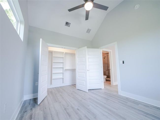 Unfurnished bedroom with high vaulted ceiling, light wood finished floors, and a closet | Image 22