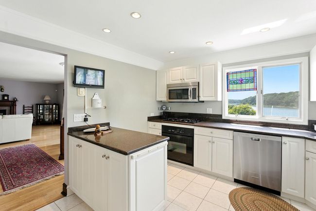 Kitchen with black appliances, dark countertops, white cabinets, recessed lighting, and light tile patterned flooring | Image 20