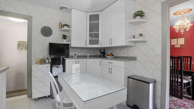 Kitchen with light tile patterned flooring, visible vents, white cabinets, and open shelves | Image 17