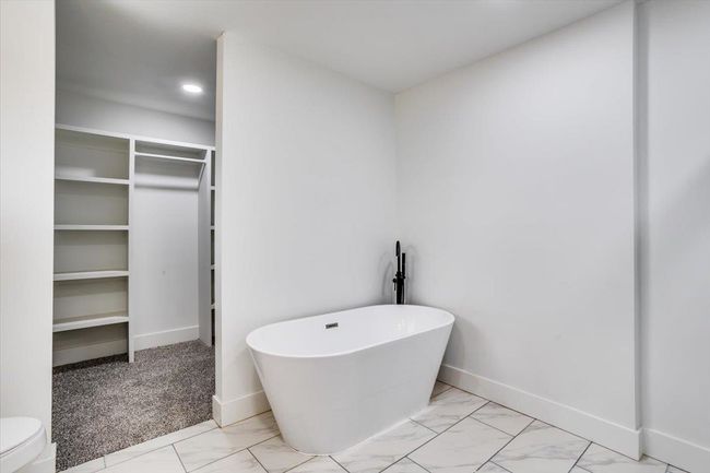 Bathroom with a freestanding tub, marble finish floor, baseboards, and a walk in closet | Image 17