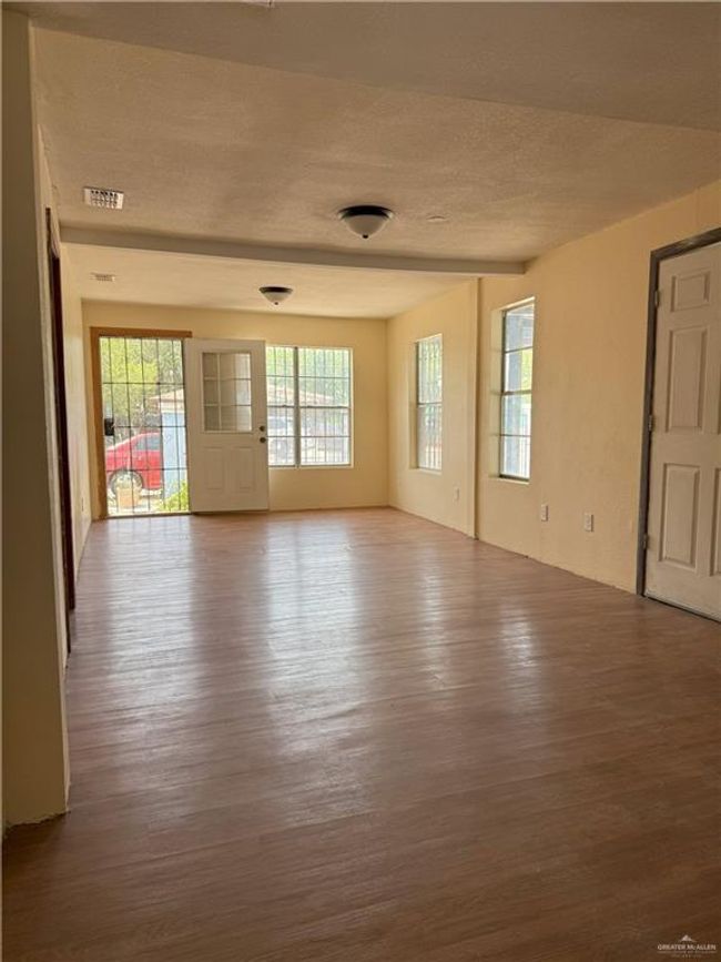Spare room featuring a textured ceiling, visible vents, a healthy amount of sunlight, and wood finished floors | Image 12