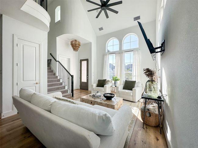 Living room featuring high vaulted ceiling, stairs, wood finished floors, a ceiling fan, and a textured wall | Image 7