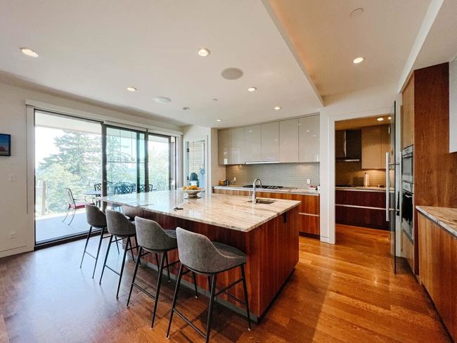 Kitchen featuring modern cabinets, light wood-style floors, backsplash, a kitchen breakfast bar, and recessed lighting | Image 12