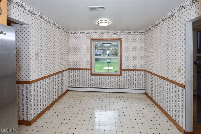 Unfurnished dining area featuring a baseboard heating unit, wallpapered walls, baseboards, and visible vents | Image 22
