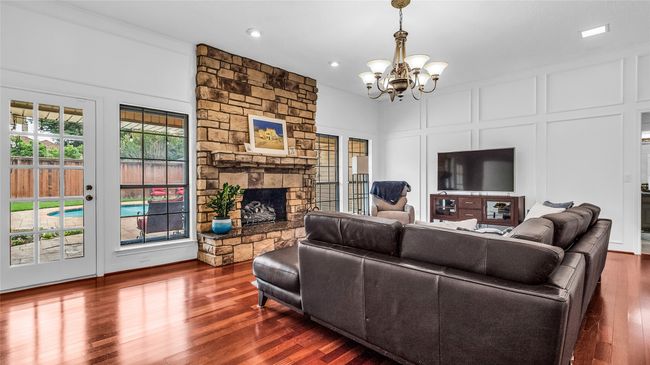 Living area with a decorative wall, a chandelier, dark wood-type flooring, a fireplace, and recessed lighting | Image 20