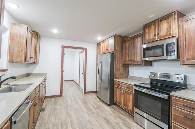 Kitchen featuring light wood-type flooring, light stone counters, sink, and stainless steel appliances | Image 9