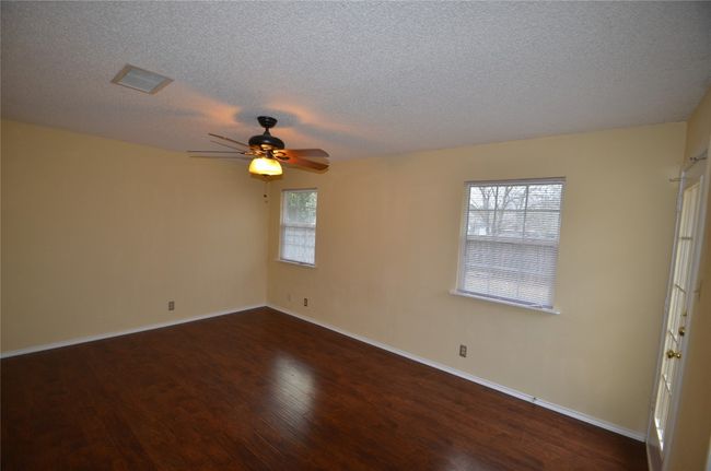 Unfurnished room with a textured ceiling, ceiling fan, dark wood-type flooring, and baseboards | Image 7
