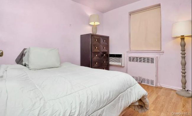 Bedroom featuring radiator, wood finished floors, and an AC wall unit | Image 11