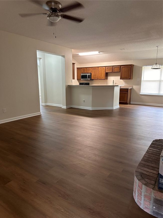 Unfurnished living room featuring dark wood-style floors, ceiling fan, baseboards, and a sink | Image 6