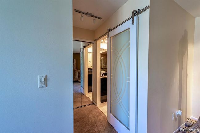 Corridor with light colored carpet, a barn door, and rail lighting | Image 23