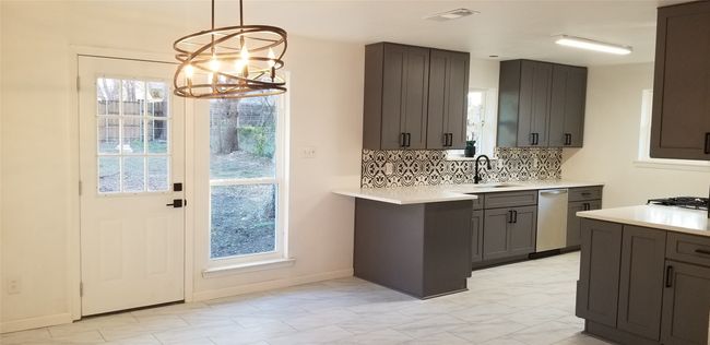 Kitchen featuring stainless steel dishwasher, a sink, a chandelier, light countertops, and backsplash | Image 16