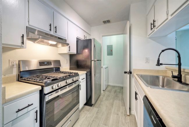 Kitchen featuring appliances with stainless steel finishes, under cabinet range hood, light countertops, and wood finish floors | Image 9