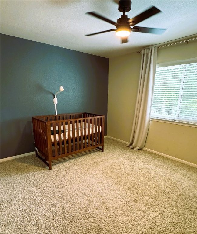 Upstairs Guest Bedroom #3 with a textured ceiling, carpet, a crib, and a ceiling fan | Image 24