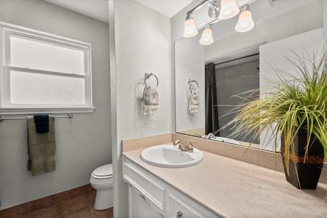 This is a modern secondary bathroom featurs a sleek countertop with a built-in sink, a large mirror, and stylish lighting. It includes a window for natural light and is accented by neutral tones throughout. | Image 30