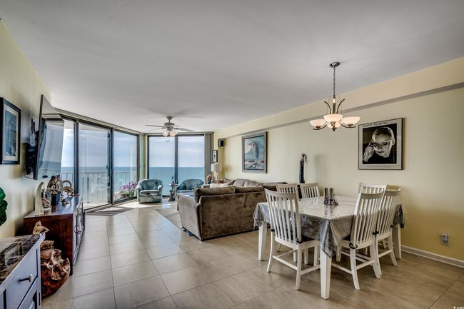Dining room featuring expansive windows, a chandelier, ceiling fan, and light tile patterned floors | Image 7