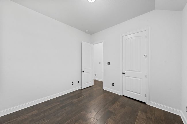 Unfurnished bedroom with dark wood finished floors and lofted ceiling | Image 26
