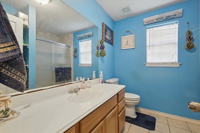 Bathroom featuring visible vents, toilet, vanity, tile patterned floors, and a stall shower | Image 28