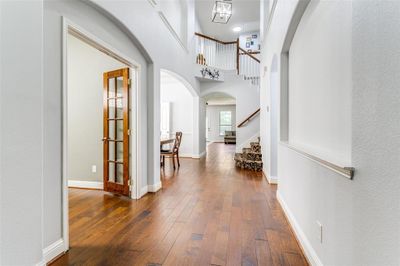 Corridor featuring a towering ceiling, dark hardwood / wood-style flooring, and an inviting chandelier | Image 2