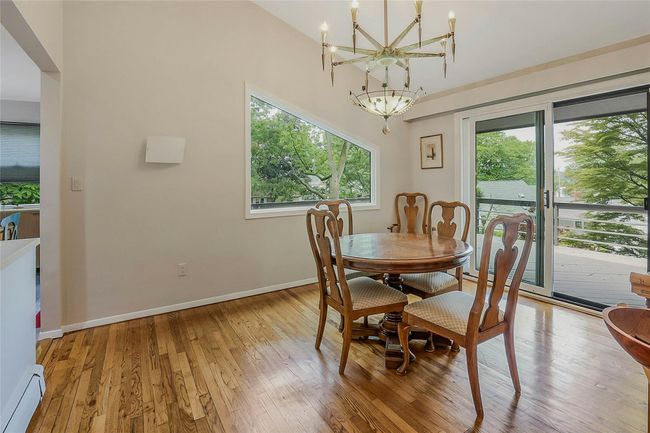 Dining room with baseboard heating, plenty of natural light, a chandelier, and light wood finished floors | Image 13