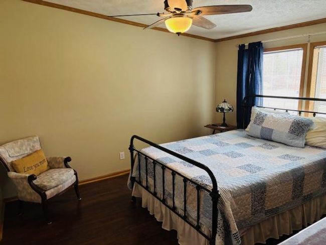 Bedroom with crown molding, ceiling fan, a textured ceiling, wood finished floors, and baseboards | Image 13