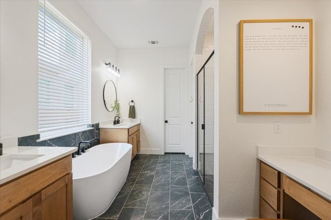 Full bath featuring marble look tile flooring, two vanities, a shower stall, and a soaking tub | Image 21