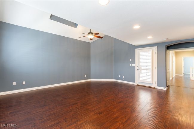 Primary bedroom with arched walkways, dark wood-style floors, baseboards, and a ceiling fan | Image 24