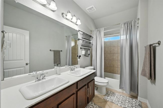 Upstairs Guest Full bath with shower / bath combination with curtain, double vanity, and tile patterned floors | Image 21