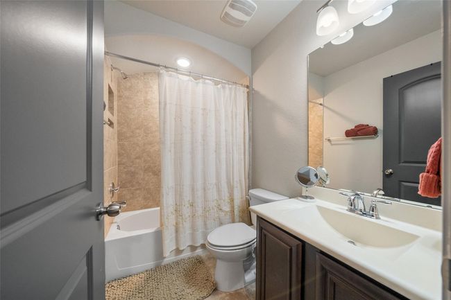 The full upstairs bathroom features a modern design with a tiled shower and tub, a large mirror above a sleek vanity with ample storage, and elegant lighting. Neutral tones create a calm, inviting atmosphere. | Image 29