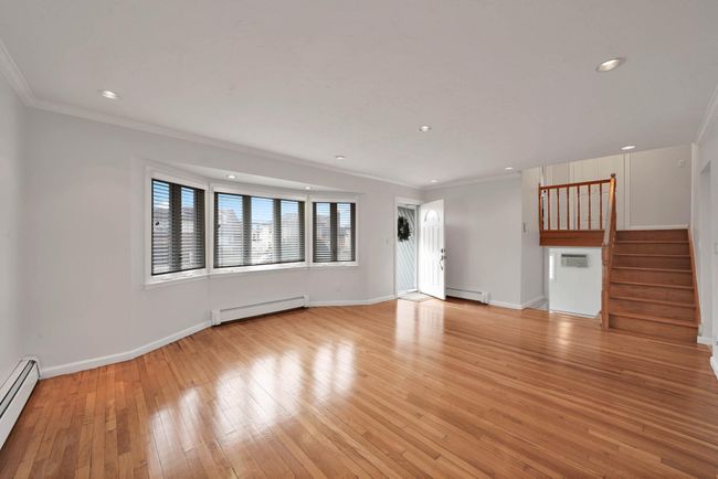 Unfurnished living room featuring baseboard heating, ornamental molding, and light hardwood / wood-style flooring | Image 5