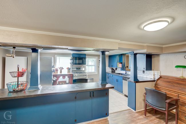 Kitchen with stainless steel range with gas cooktop, dishwasher, dark countertops, blue cabinets, and crown molding | Image 11