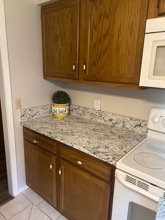 Kitchen with white appliances, light tile patterned floors, and light stone countertops | Image 10