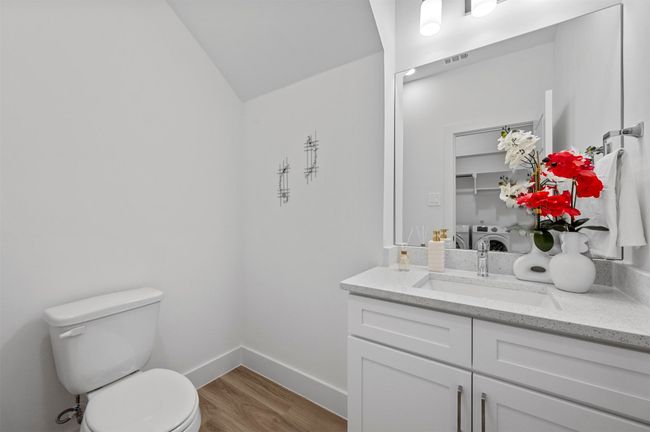 Half bathroom featuring independent washer and dryer, vanity, wood finished floors, and vaulted ceiling | Image 19