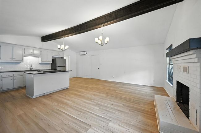 Kitchen with freestanding refrigerator, a chandelier, dark countertops, a fireplace, and light wood-type flooring | Image 4