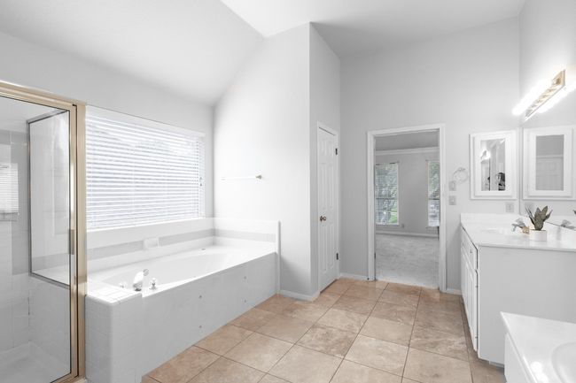 Full bath featuring vanity, a garden tub, a stall shower, and lofted ceiling | Image 28