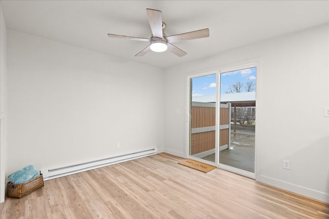 Empty room featuring wood finished floors, a baseboard radiator, and ceiling fan | Image 9