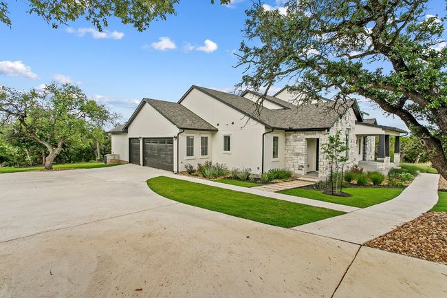 View of front of home with a garage, stone siding, a shingled roof, and a front yard | Image 34