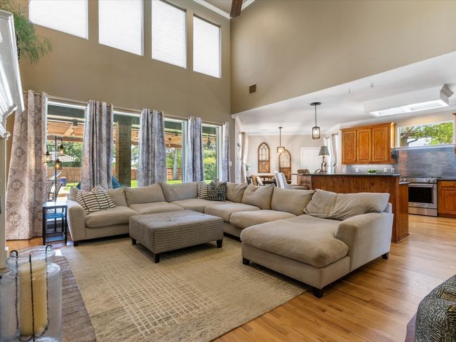 Living area featuring light wood finished floors, plenty of natural light, a towering ceiling, and crown molding | Image 15