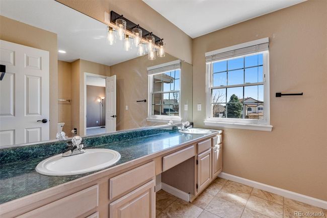 Bathroom with toilet, double vanity, a sink, and baseboards | Image 23