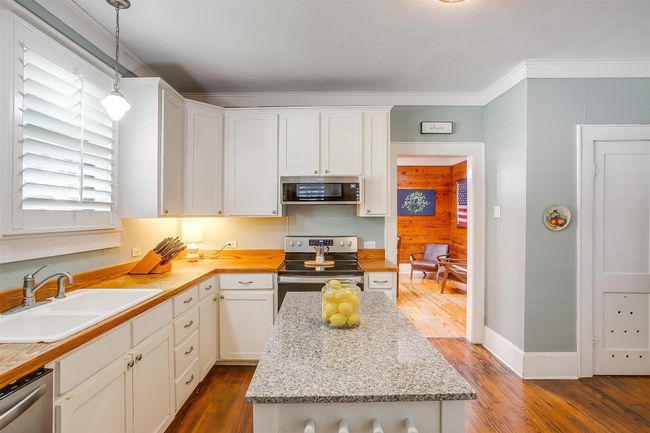 Kitchen with appliances with stainless steel finishes, dark wood-style flooring, white cabinetry, and crown molding | Image 26