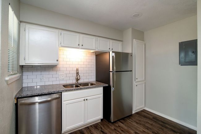 Kitchen featuring decorative backsplash, a sink, appliances with stainless steel finishes, electric panel, and dark wood-style flooring | Image 8