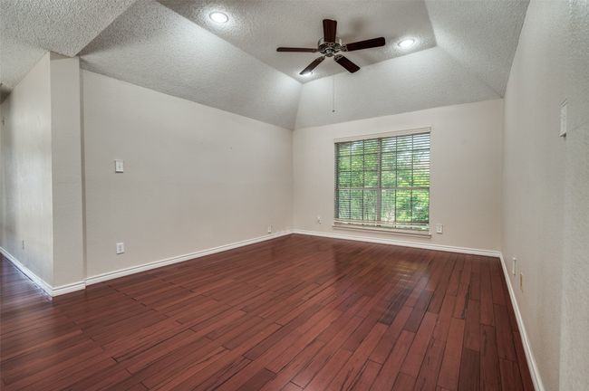 Empty room featuring lofted ceiling, ceiling fan, baseboards, a textured ceiling, and dark wood-style flooring | Image 23