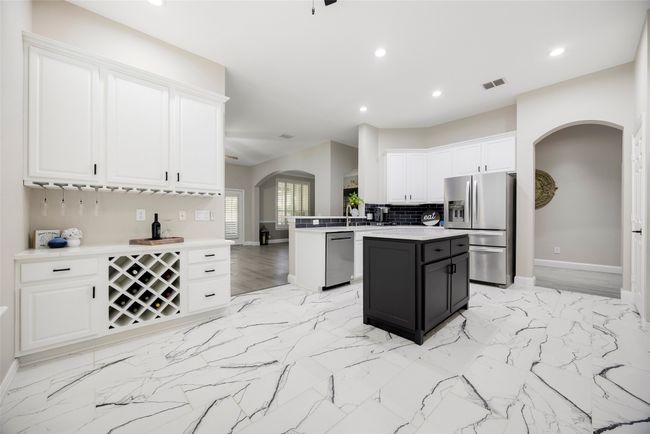 Kitchen featuring arched walkways, white cabinetry, stainless steel appliances, recessed lighting, and baseboards | Image 5