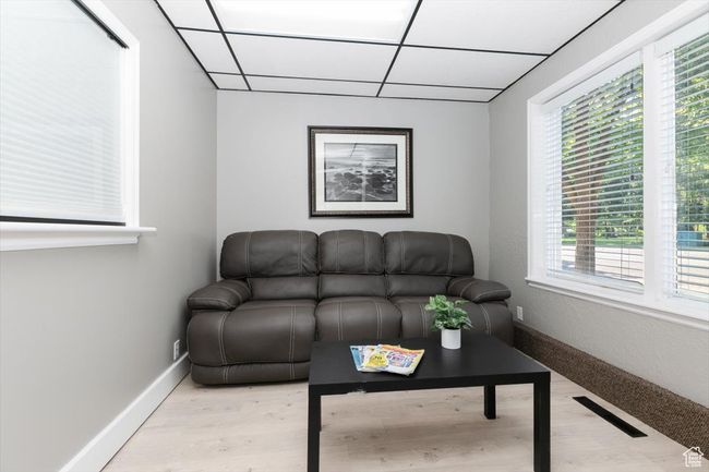 Living area with a drop ceiling and light wood-style flooring | Image 5