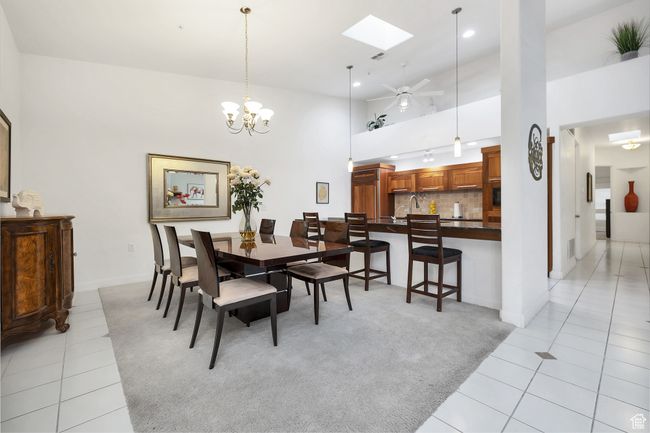 Dining space featuring light colored carpet, light tile patterned floors, a towering ceiling, and a skylight | Image 9