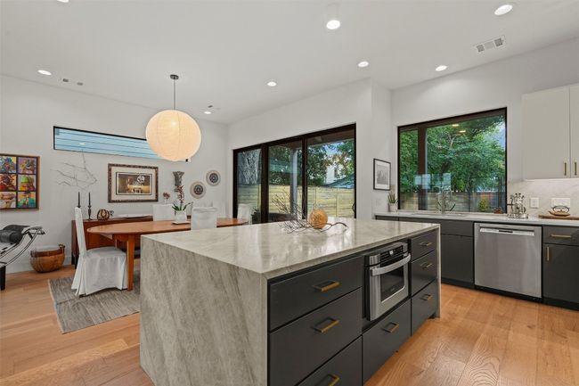 Kitchen with appliances with stainless steel finishes, light wood-style floors, a kitchen island, light stone countertops, and recessed lighting | Image 15