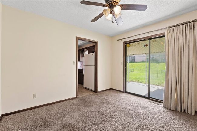 Spare room featuring light carpet, a textured ceiling, ceiling fan, and baseboards | Image 8