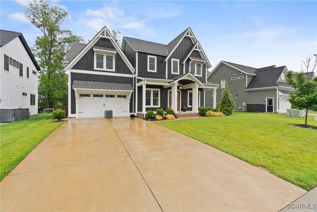 Craftsman inspired home featuring board and batten siding, driveway, a front yard, a garage, and central AC | Image 43