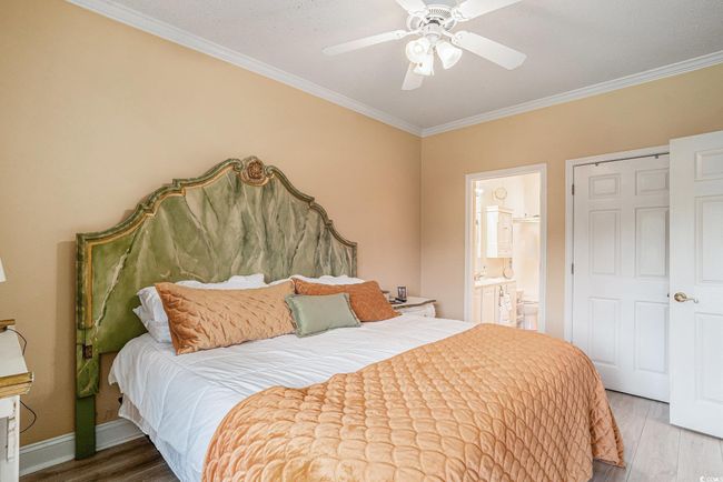 Bedroom featuring wood finished floors, ornamental molding, ensuite bathroom, and ceiling fan | Image 13