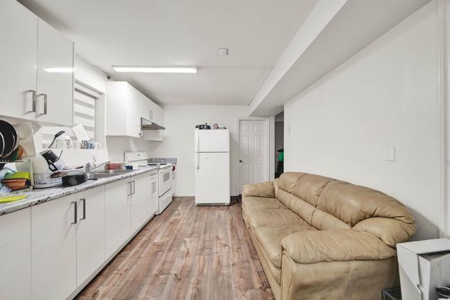 Kitchen featuring white appliances, under cabinet range hood, light wood-type flooring, and white cabinets | Image 8
