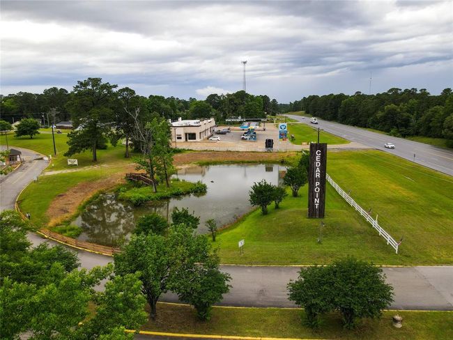 Cedar point subdivision entrance with pond and large trees. This is a twenty four seven manned gated community. There are golf carts and people waving and enjoying a relaxed welcoming atmosphere. The drive to your home feels like a vacation destination with curving hilly roads and water views of ponds and Lake Livingston. Notice the bridge over to the little island in the pond! | Image 45
